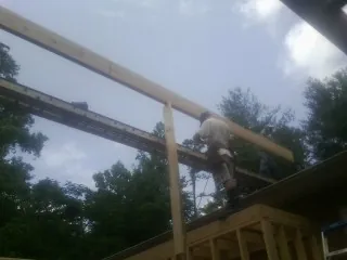 Carpenter setting a ridge beam over a new addition frame — Ice Dam Removal by Roofing Brothers in Braggs