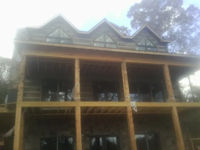 Dormers and porch framing on a large log home under construction — Roof Coating work by our crew in Braggs