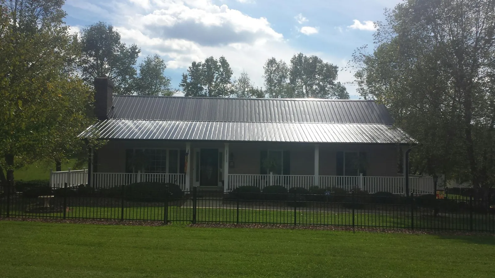 Gray metal roof on a brick ranch with a full width front porch — Gutter Guard Installation work by our crew in Braggs