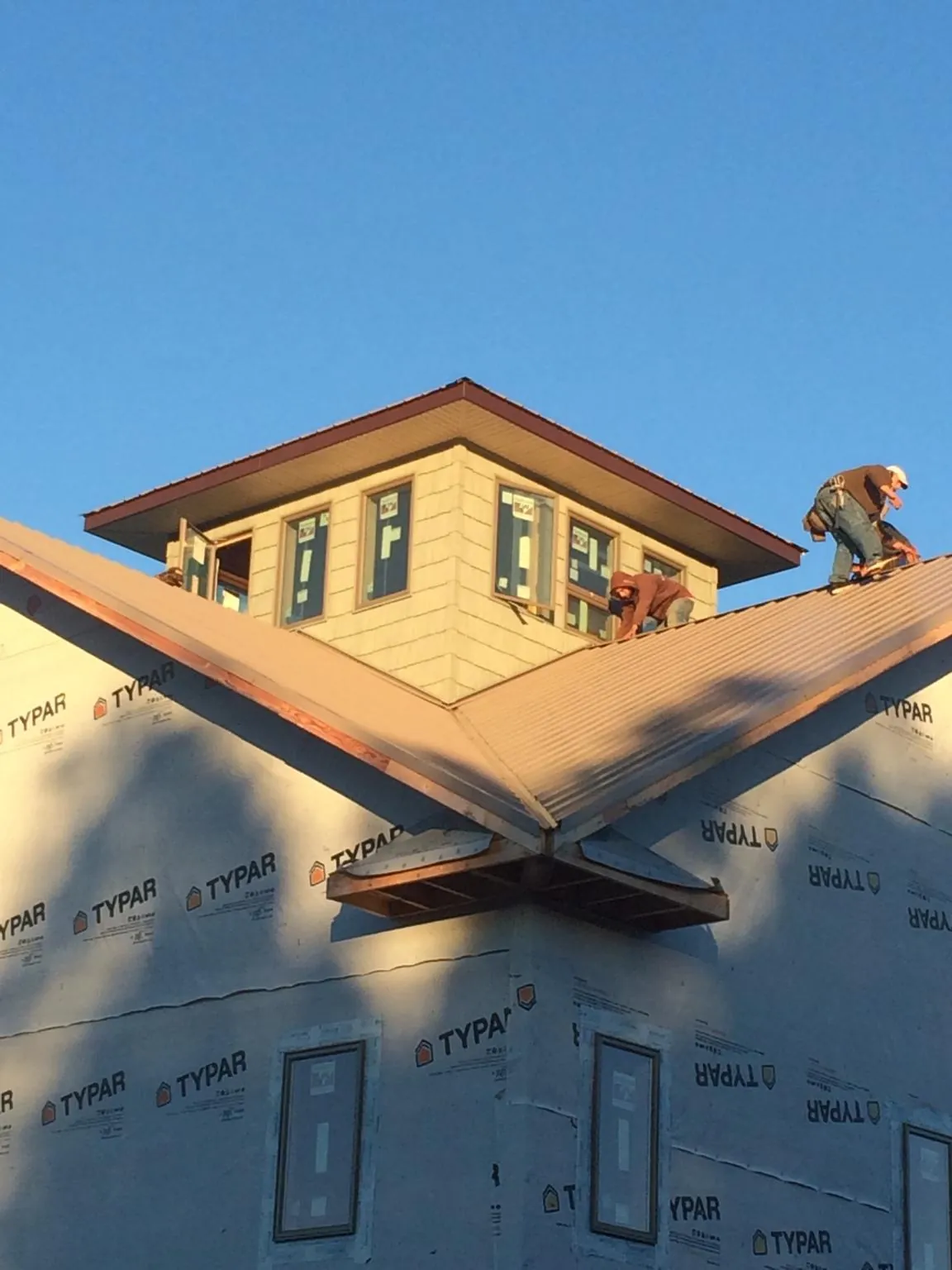 Roofers working around a rooftop cupola on a new metal roof at sunset — Roof Waterproofing in Braggs by Roofing Brothers